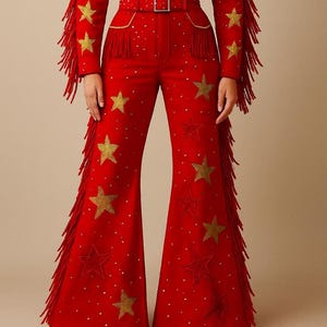 May include: A red western-style outfit with gold star embellishments. The outfit includes a jacket with fringe and star details, and flared pants with star patterns and fringe along the sides. The outfit is cinched at the waist with a belt.