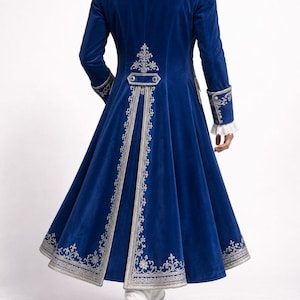 Peut inclure: Manteau en velours bleu roi avec broderies argent&eacute;es et &eacute;paulettes &agrave; franges. Le long manteau pr&eacute;sente des d&eacute;tails orn&eacute;s sur le col, les poignets et le dos, avec une jupe &eacute;vas&eacute;e. Des bottes blanches compl&egrave;tent le look.