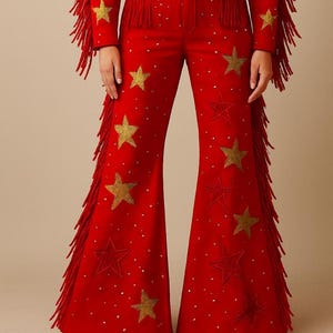 May include: Red flared pants with gold star and dot embellishments. The pants have gold fringe along the sides and are part of a matching set. The outfit is a bold, eye-catching design.