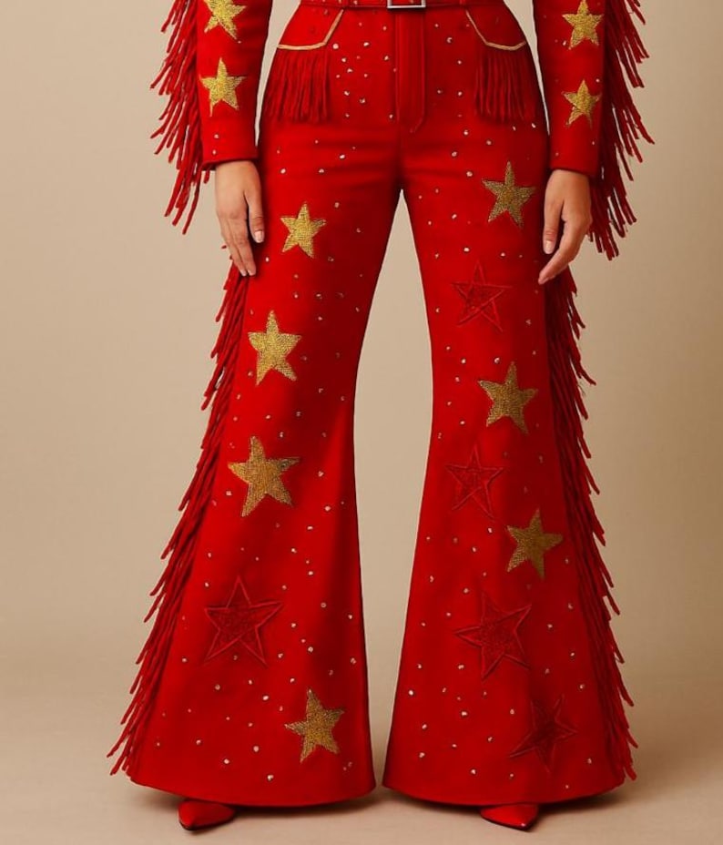 May include: Red flared pants with gold star and dot embellishments. The pants have gold fringe along the sides and are part of a matching set. The outfit is a bold, eye-catching design.