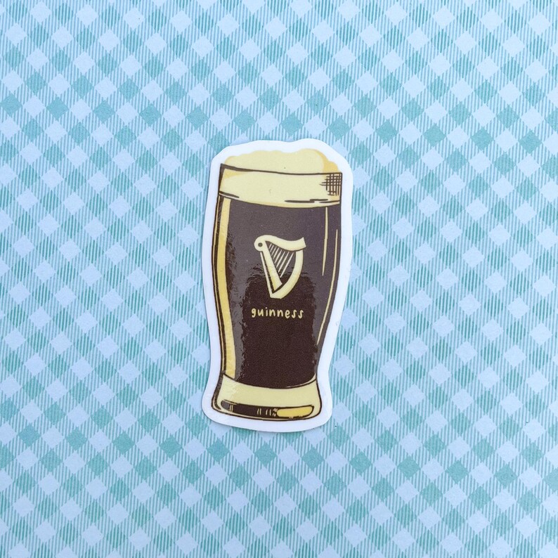 Puede incluir: Una pegatina que representa una pinta de Guinness. El vaso est&aacute; lleno de cerveza oscura y coronado con espuma cremosa. El logotipo de Guinness, un arpa, es visible, con el nombre de la marca debajo.
