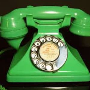 May include: A vintage green rotary dial telephone with a white dial and black numbers. The phone has a square base and a cord with a braided green cord.