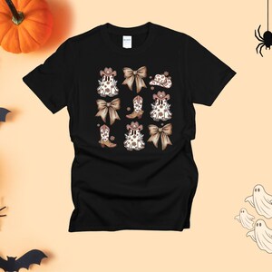 May include: Black t-shirt featuring a repeating pattern of cowboy boots, bows, and hats in brown and white. The design has a country western theme. The shirt is made of a soft material and is suitable for casual wear.
