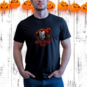 May include: Black t-shirt featuring a graphic of a scary clown with red hair and a red balloon. The text "YOU'LL FLOAT TOO!" is printed in red. The shirt is perfect for Halloween.