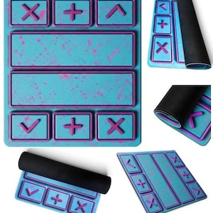 May include: A rectangular desk mat featuring a bright turquoise surface with a pink paint splatter pattern. The mat includes raised purple borders forming geometric shapes and mathematical symbols like plus and multiplication signs, with a black underside.