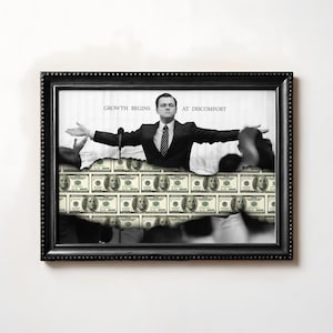 Può includere: Stampa incorniciata in bianco e nero raffigurante un uomo in giacca e cravatta con le braccia tese, posto di fronte a uno sfondo di banconote da 100 dollari. Il testo "GROWTH BEGINS AT DISCOMFORT" è sopra l'uomo. La cornice è nera con un bordo strutturato.