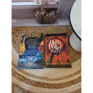 May include: Two paperback books placed side by side. The left book is titled The Magical Worlds of the Lord of the Rings by David Colbert, featuring blue and gold fantasy artwork. The right book is titled Harry Potter and the Bible by Richard Abanes.