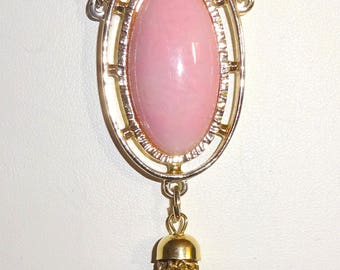 May include: A gold chain necklace with a pink oval stone set in a gold frame. The necklace has a gold tassel pendant.