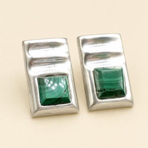 May include: A pair of rectangular silver earrings featuring a smooth, polished finish with a curved top section and a square, faceted green malachite gemstone set in the center of each piece, showcasing natural dark green banding patterns.