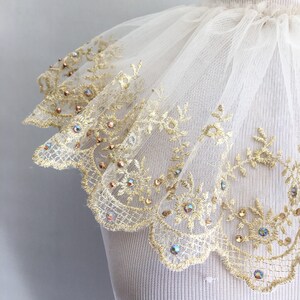 May include: A white tulle collar with a gold lace trim and iridescent rhinestones.