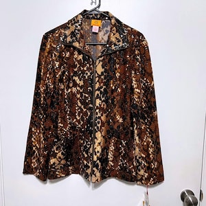 May include: A brown, black, and tan snakeskin-patterned jacket with a full-length zipper. The jacket is hanging on a black hanger against a white background. The collar and shoulders have a decorative trim. A tag hangs from the bottom.