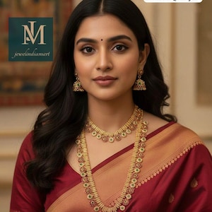 Puede incluir: Una mujer luce un conjunto de joyas doradas, que incluye un collar y pendientes, con detalles rojos y verdes. Las joyas se combinan con un sari de color granate. La imagen incluye el texto "NO:22518-535 Matt Combo Set Premium Quality A+".
