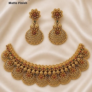 May include: A gold-toned necklace and matching pair of drop earrings with a matte finish. The jewelry features intricate floral motifs, filigree patterns, and small red and green accents. Text on the image reads: No.7501-220, Priemum Quality, Matte Finish.