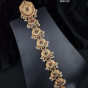 May include: A gold-toned hair accessory featuring a matte finish and a series of circular, ornate medallions. Each medallion is decorated with small red and green stones and accented with white beads. Text reads: No. 1102-300 matte finish Primium Quality Jade set.