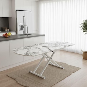 May include: A white and grey marble-effect table with a white metal base. The table is on a beige rug in a modern kitchen. The table's height is adjustable, with a length of approximately 120 cm.