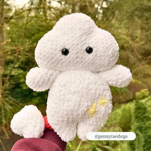 Op de afbeelding: Een witte, pluche wolk-vormige knuffel met zwarte knoopogen en kleine armen en benen. Het speelgoed heeft een gele sterren design aan de zijkant. De tekst "@pennyraeshops" staat onderaan de afbeelding. Het speelgoed is zacht en pluizig.