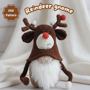 May include: A handmade crochet reindeer gnome with a brown hat, antlers, and arms. The gnome has a white beard, a red nose, and a white face. The text "Reindeer gnome" is above the gnome, and "PDF Pattern" is in the corner.