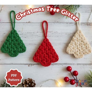 May include: Three crocheted Christmas tree ornaments in green, red, and cream colors. Each tree has a loop for hanging. The image includes the text "Christmas Tree Glitter" and "PDF Pattern".
