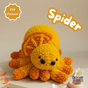 May include: A handmade crocheted spider toy in yellow and orange. The spider has a round body, eight legs, and black eyes. The word "Spider" is written in white script. The image also includes the text "PDF Pattern".