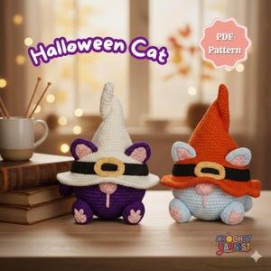 May include: Two crocheted Halloween cat figures. One is purple with a white witch hat, the other is light blue with an orange hat. Both have black bands with gold buckles. The image includes the text "Halloween Cat" and "PDF Pattern".