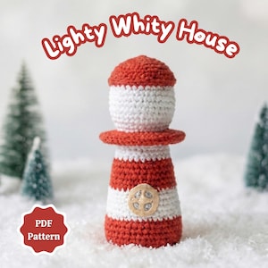 Op de afbeelding: Een gehaakte vuurtoren in rood-witte strepen, met een rode bovenkant en een klein houten knoopdetail. De tekst "Lighty Whity House" is boven de vuurtoren gebogen. Een rode badge met de tekst "PDF Pattern" staat in de linker benedenhoek.