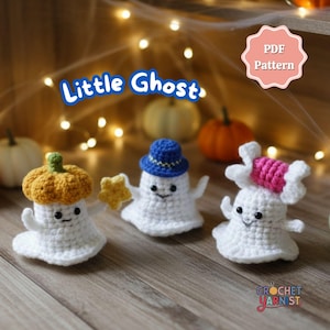 May include: Three white crochet ghost figures with smiling faces, each wearing a different hat: a pumpkin, a blue hat, and a pink candy. The text "Little Ghost" is above the figures, and "PDF Pattern" is in a pink circle. The background includes pumpkins and fairy lights.