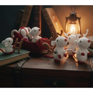 May include: A collection of handmade crochet Christmas decorations. The scene includes white mice with red noses and feet, a red sleigh, and reindeer. The decorations are arranged on a wooden surface with books and a lantern in the background.