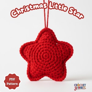 May include: A handmade, red crocheted star ornament with the text "Christmas Little Star" in a whimsical font. The star is suspended by a red string, perfect for holiday decor. The image also includes a "PDF Pattern" badge.