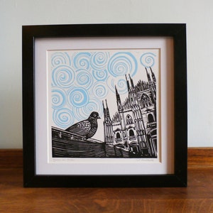 May include: A black and white linocut print of a cathedral with a pigeon perched on a ledge. The sky is a light blue with swirling patterns.