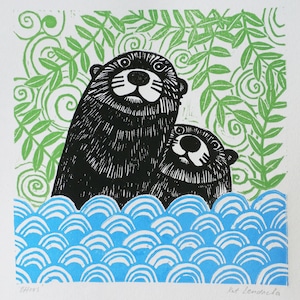 May include: A linocut print of two otters swimming in blue water with green foliage in the background. The print is titled "Otters" and signed "Kat Theodosia".
