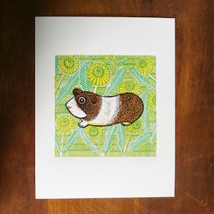 May include: A brown and white guinea pig with black eyes is standing in a field of green and yellow flowers. The guinea pig is looking to the left of the image.