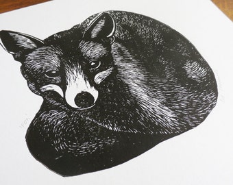 May include: Black and white woodcut print of a fox curled up sleeping. The fox is depicted in a realistic style with detailed fur and facial features.