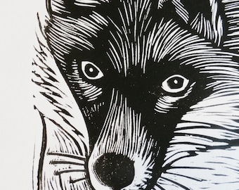 May include: Black and white woodcut print of a fox's face. The fox is looking directly at the viewer with a serious expression. The fur is detailed with fine lines.