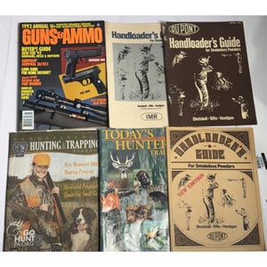 Puede incluir: Una colección de revistas y guías antiguas relacionadas con la caza y las armas de fuego. Los títulos incluyen "Guns & Ammo", "Handloader's Guide" y "Today's Hunter". Las portadas presentan imágenes de armas, cazadores y fauna.