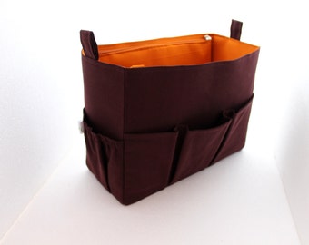 May include: A brown fabric organizer with multiple pockets and an orange lining. The organizer is designed to fit inside a handbag.