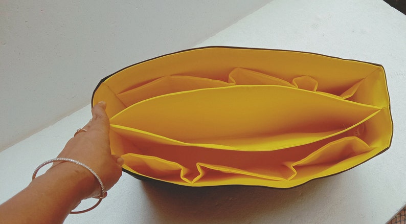 May include: Yellow fabric organiser with multiple compartments for a tote bag.