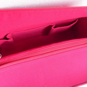 May include: Pink fabric bag organiser with multiple pockets and a zipped compartment. The organiser is designed to fit inside a larger bag.