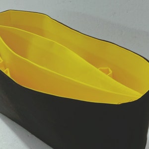May include: A black fabric tote bag with a yellow fabric lining. The lining has three compartments.
