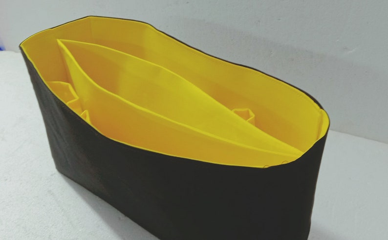 May include: A black fabric tote bag with a yellow fabric lining. The lining has three compartments.
