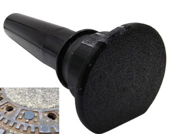 Puede incluir: Un tapón negro con una cabeza circular texturizada. El objeto tiene un mango cilíndrico y probablemente está diseñado para sellar un desagüe o una abertura similar. El diseño es simple y funcional.