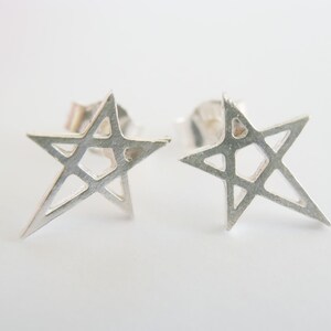 May include: A pair of silver star-shaped earrings with a geometric design. The earrings are made of a thin metal and have a delicate, intricate design.