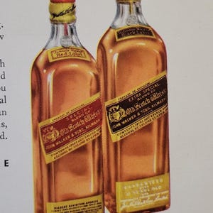 Puede incluir: Dos botellas vintage de whisky escoc&eacute;s John Walker. La botella de la izquierda est&aacute; etiquetada como "Red Label" y la de la derecha como "Black Label". Ambas botellas tienen etiquetas y tapones dorados, con texto y gr&aacute;ficos. Las botellas se muestran sobre un fondo blanco.