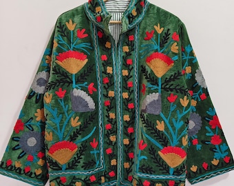 May include: A green velvet jacket with colourful floral embroidery. The jacket has a high collar, a zip closure, and is decorated with red, yellow, blue, and grey flower designs. The lining has a striped pattern.