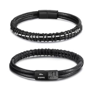 May include: Two black leather bracelets. One has silver beads and bars. The other has a black clasp with the engraved initials "k&m", the date "20210112", and a small photo. The bracelets are likely for a wrist size of approximately 18 cm.