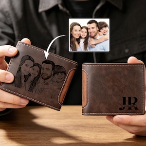 May include: A brown leather wallet featuring a family portrait engraving. The bi-fold wallet has a contrasting brown panel and white stitching. The initials "JR" and the name "Jeremiah" are printed on the wallet.