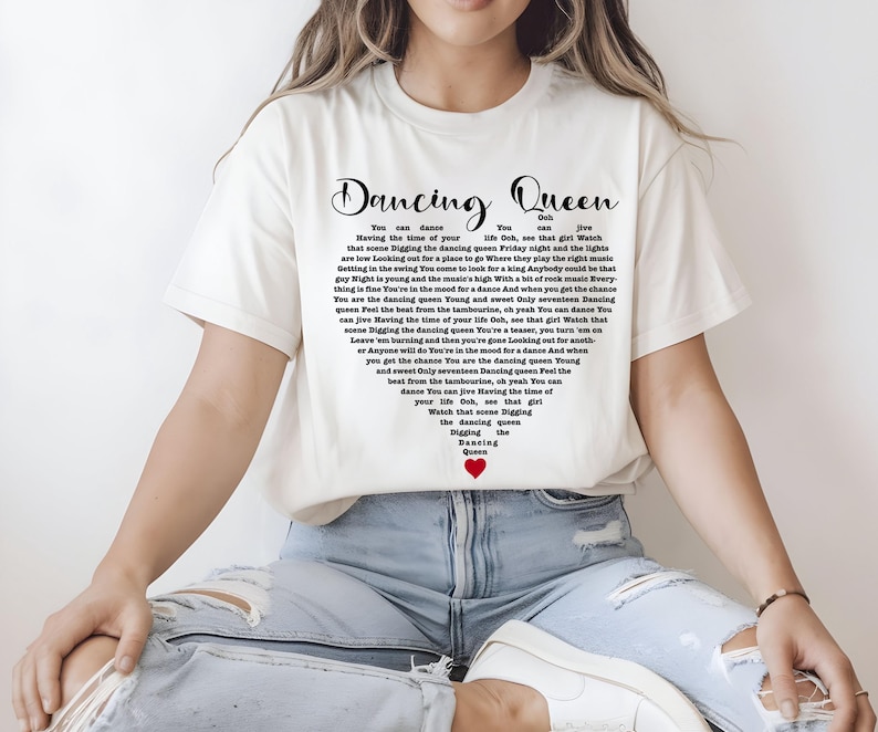 A person wearing a white t-shirt with text printed on it, sitting with their legs crossed.