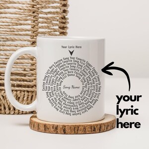 May include: White ceramic mug with a black circular design of song lyrics and the words "Your Lyric Here" and "Song Name". The mug sits on a wooden coaster.