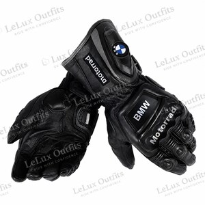 Pode incluir: Um par de luvas de motociclista pretas com o logótipo da BMW e a palavra Motorrad impressa nos punhos e nós dos dedos. As luvas têm acolchoamento reforçado nos dedos e palmas, com um emblema circular da BMW na zona do pulso.