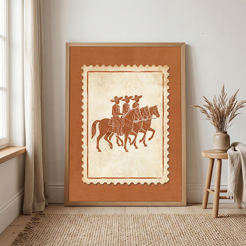 May include: A framed wall art print featuring a cream-colored postage stamp design on a solid terracotta background. The stamp illustration depicts three figures wearing wide-brimmed hats riding horses in profile, rendered in a dark brown line art.