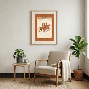 May include: A framed wall art print featuring a postage stamp design with a terracotta background. The central illustration depicts three figures riding horses in a line, rendered in a dark brown outline style on a cream-colored textured background.